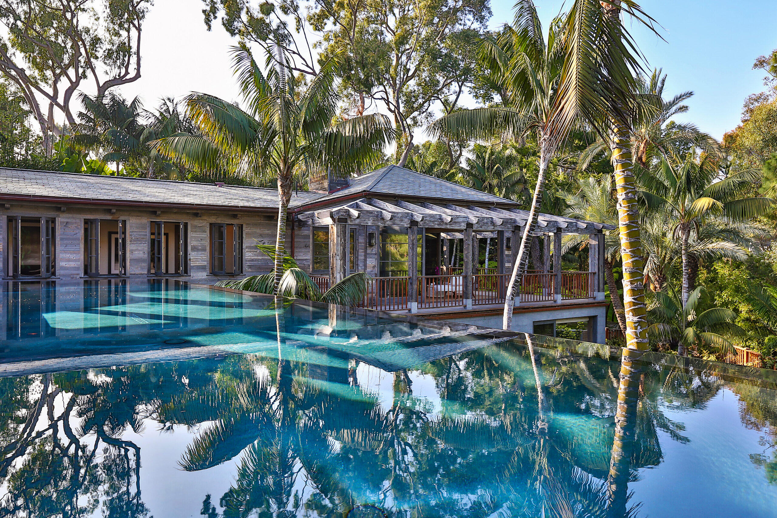 Custom Malibu residence featuring reclaimed wood cladding reflected in infinity-edge pool by Hayne Architects