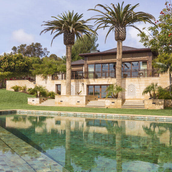 Rear Facade of a Malibu Residence featuring infinity-edge pool, natural stone cladding and clay tile roof by Hayne Architects.