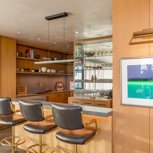 Kitchen and Bar in West Hollywood apartment by Hayne Architects featuring white oak and porcelain front cabinetry, porcelain tile panel countertops by Laminam and a mirrored bar shelf.