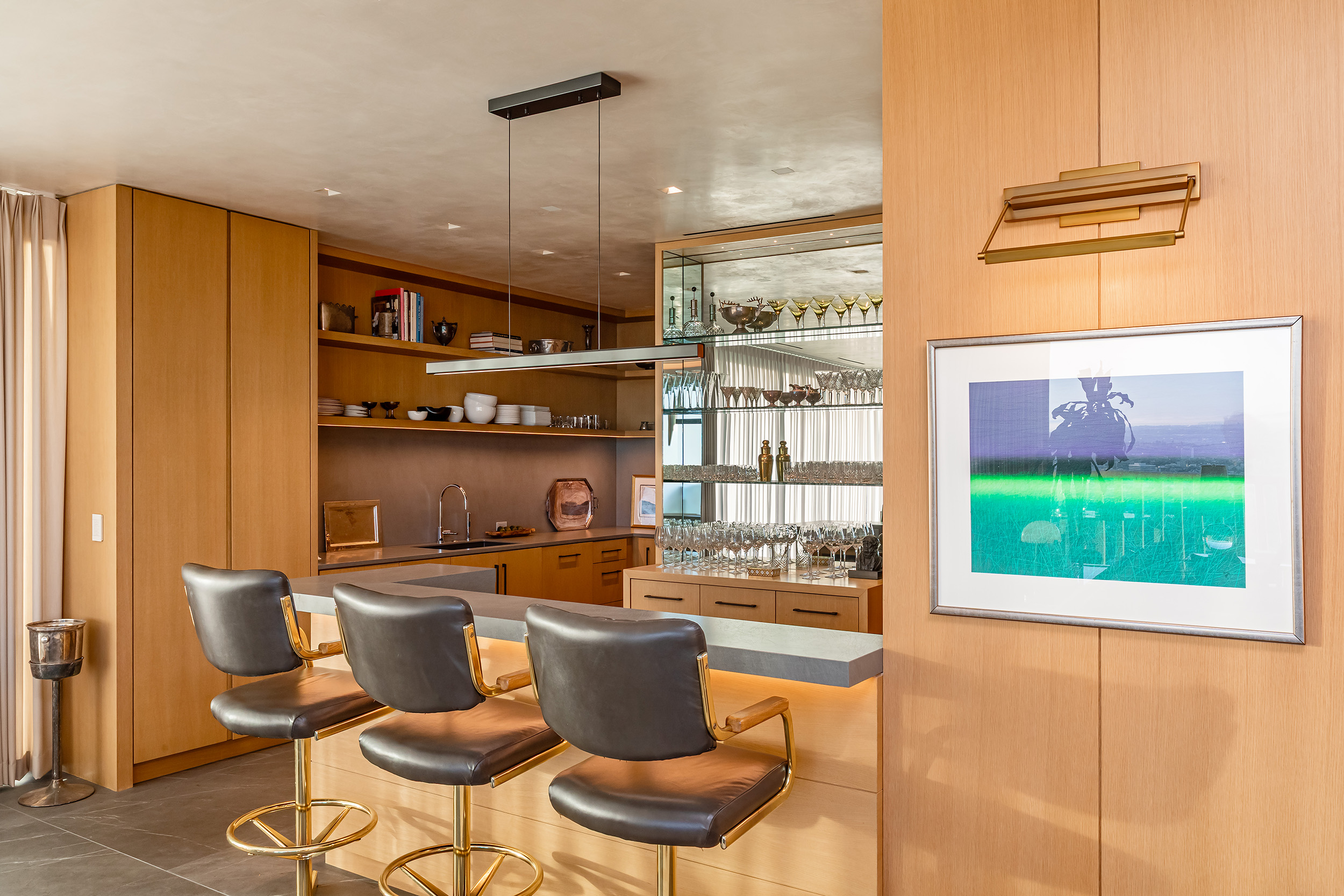 Kitchen and Bar in West Hollywood apartment by Hayne Architects featuring white oak and porcelain front cabinetry, porcelain tile panel countertops by Laminam and a mirrored bar shelf.