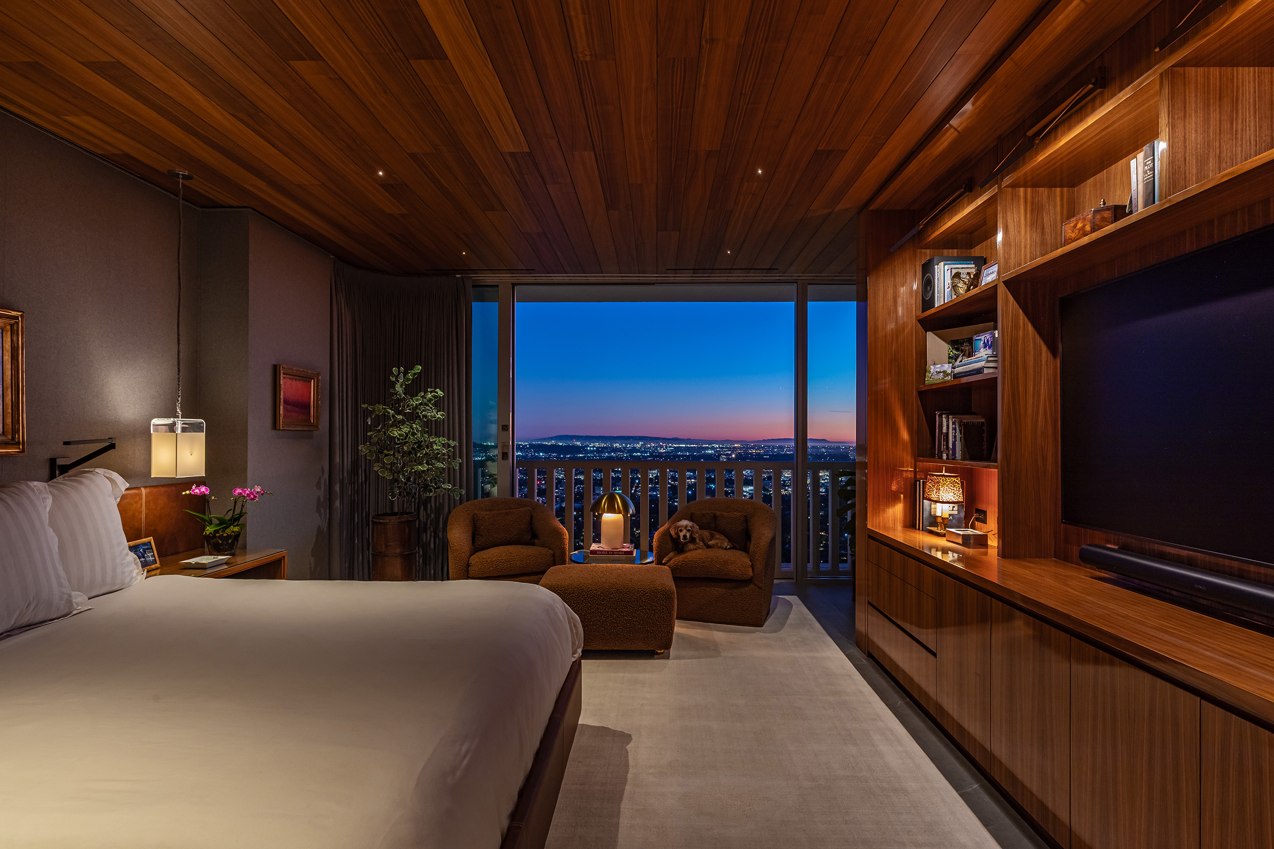 Bedroom in West Hollywood apartment by Hayne Architects featuring walnut plank ceiling, walnut built-in bookcase and full-height sliding glass doors.