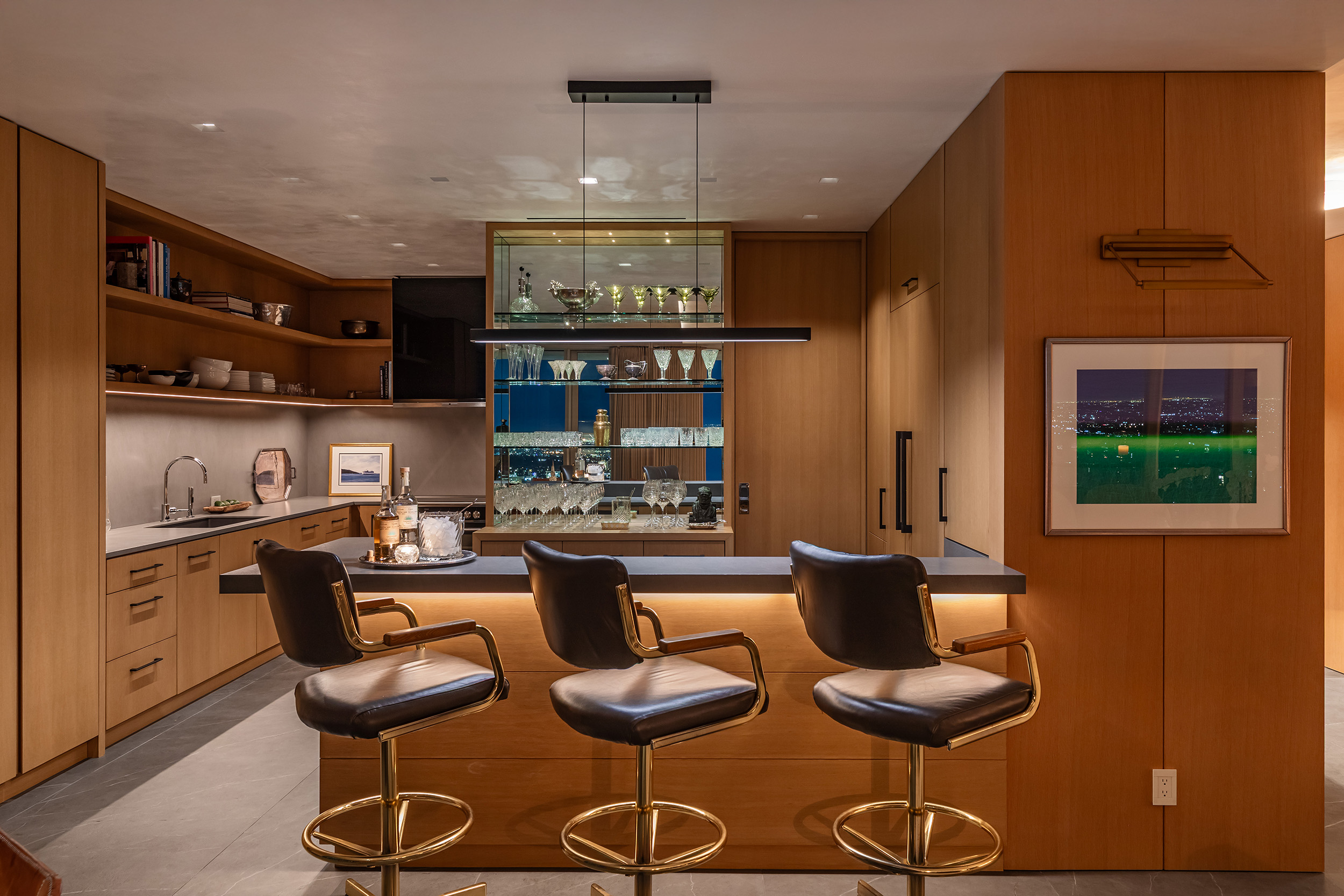 Kitchen and Bar in West Hollywood apartment by Hayne Architects featuring white oak and porcelain front cabinetry, porcelain tile panel countertops by Laminam and a mirrored bar shelf.