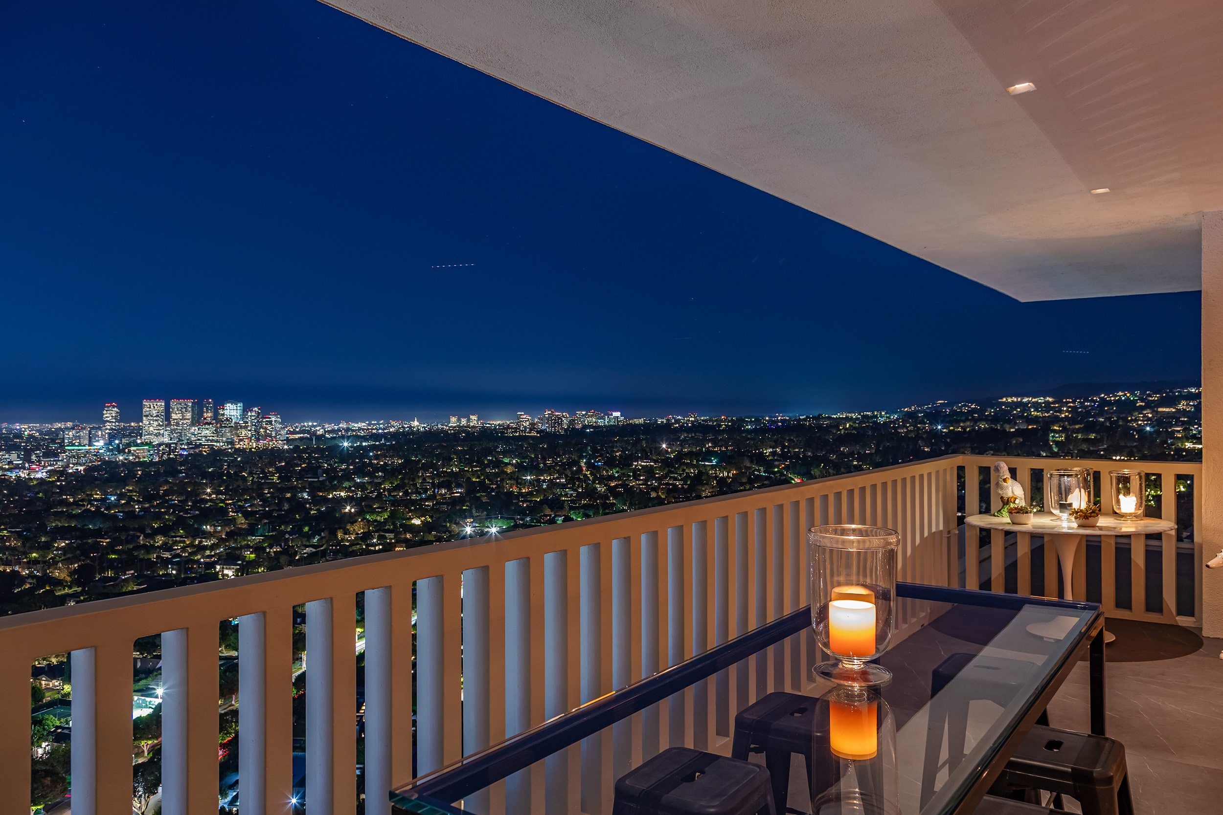 Exterior Balcony at night in West Hollywood apartment by Hayne Architects featuring, large format tile decking and view of city.